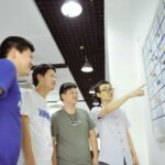 Four men gathered around a whiteboard with sticky notes.