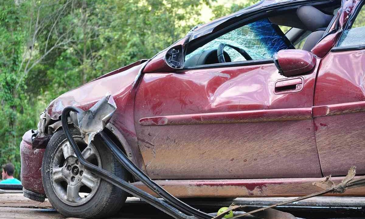 Voiture rouge avec dommage au pare-chocs et au pneu, sur une route entourée de verdure
