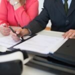 Deux personnes signant des documents à une table de bureau