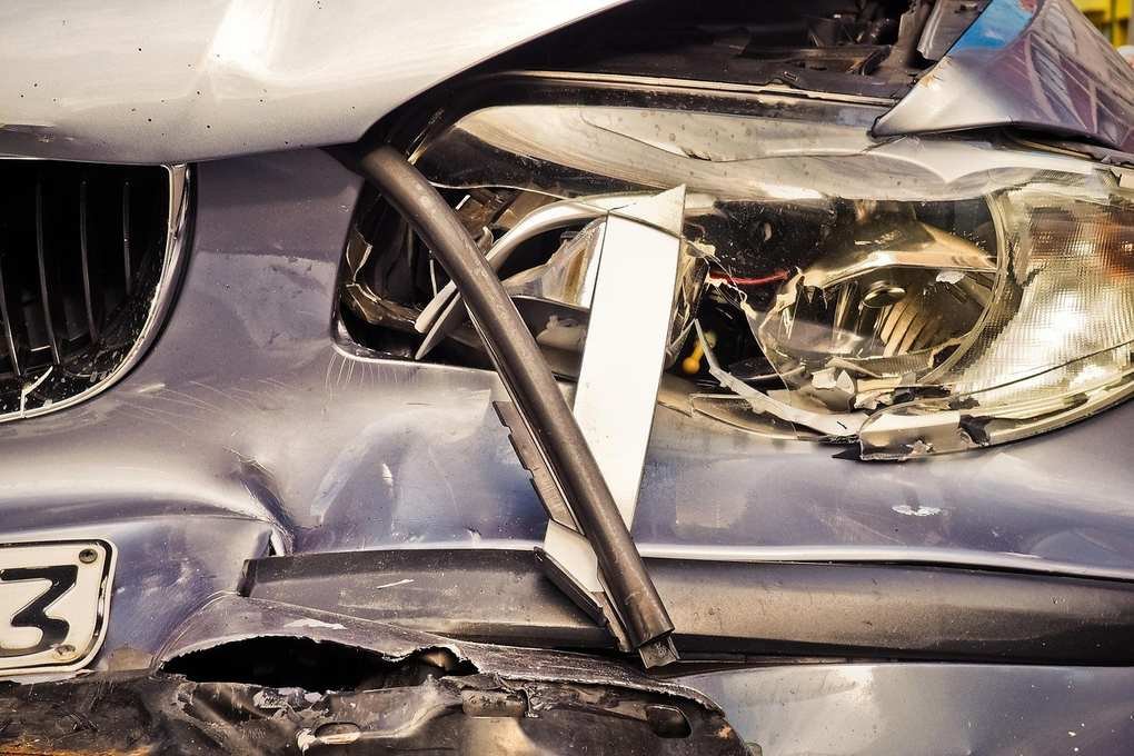 Détail d'une voiture impliquée dans un accident, montrant des dommages au phare et à la grille