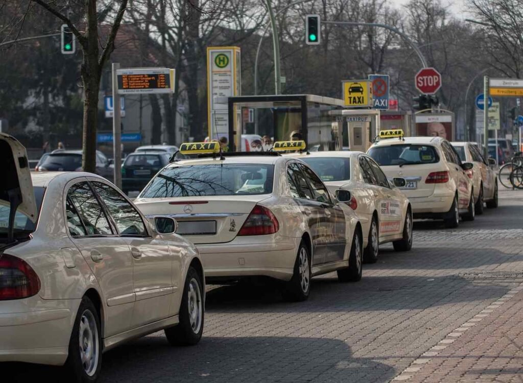 Une rangée de taxis blancs attend au feu rouge