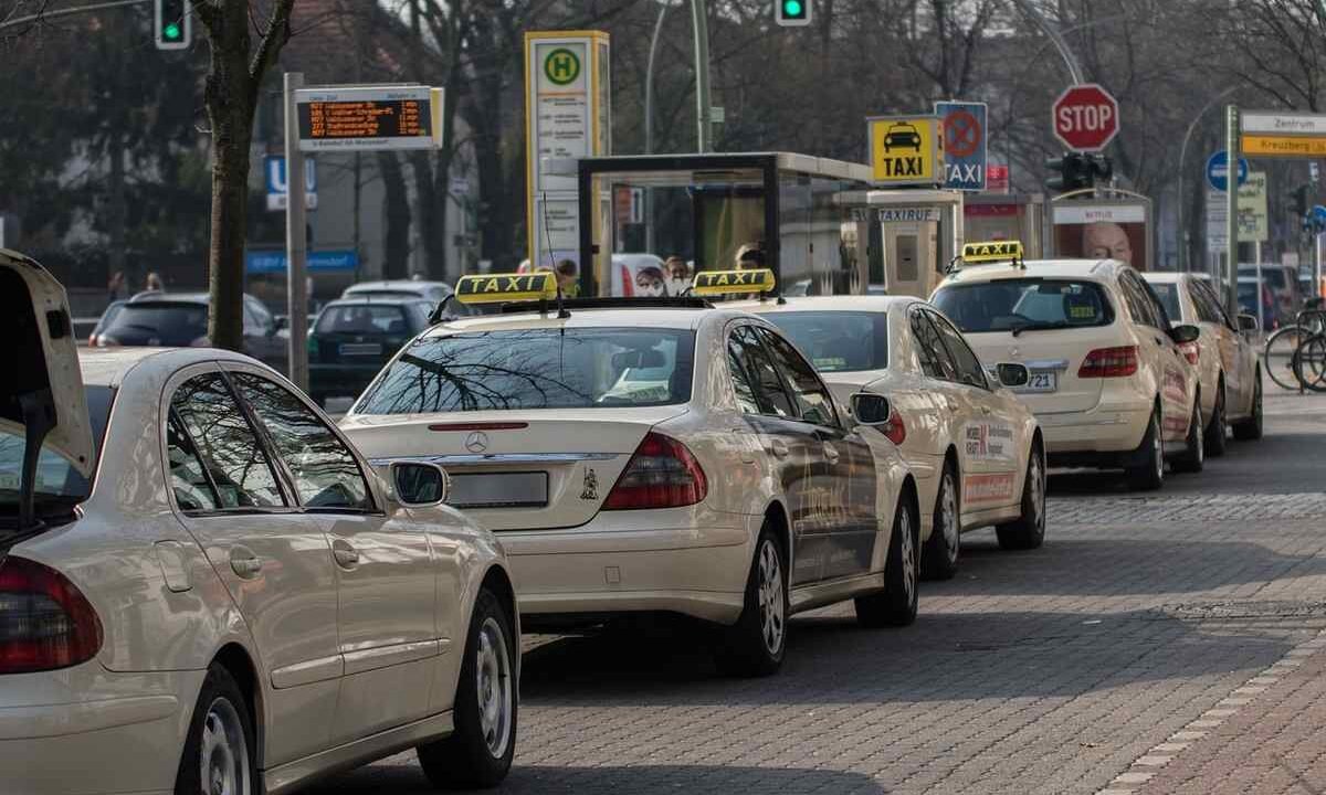 Une rangée de taxis blancs attend au feu rouge