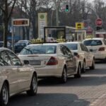 Une rangée de taxis blancs attend au feu rouge