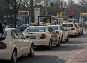 Une rangée de taxis blancs attend au feu rouge