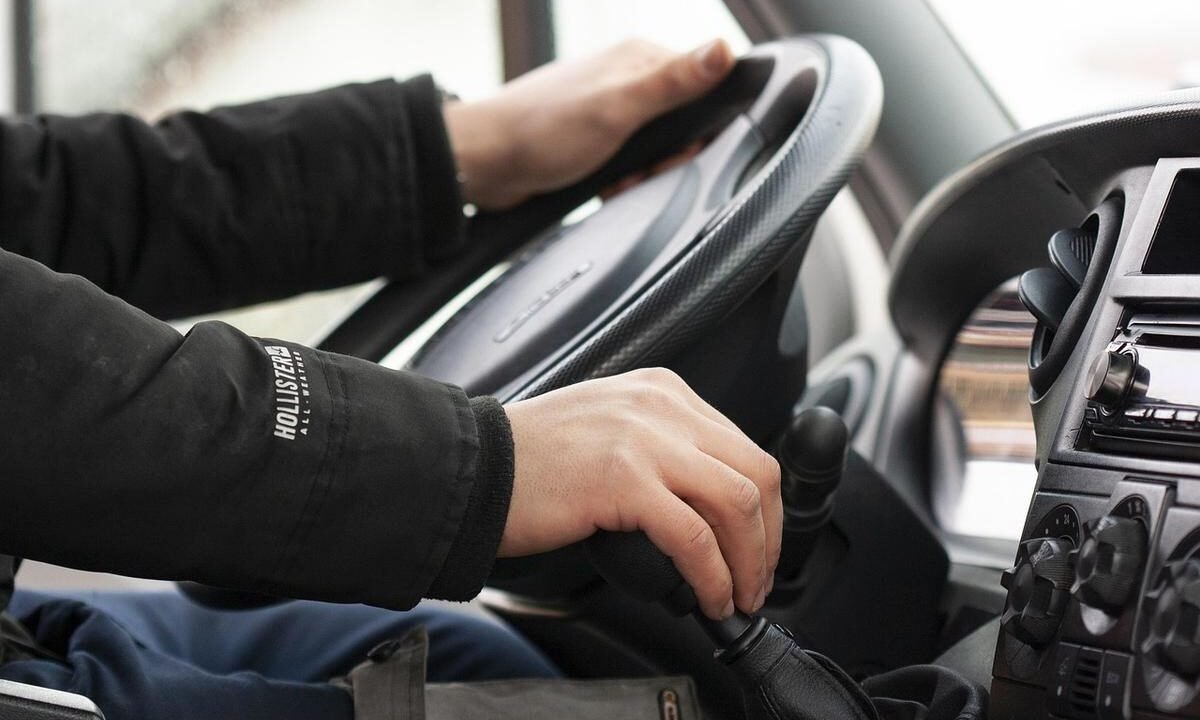 Mains sur le volant et le levier de vitesses d'une voiture
