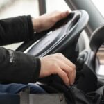 Mains sur le volant et le levier de vitesses d'une voiture