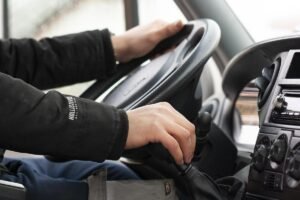 Mains sur le volant et le levier de vitesses d'une voiture