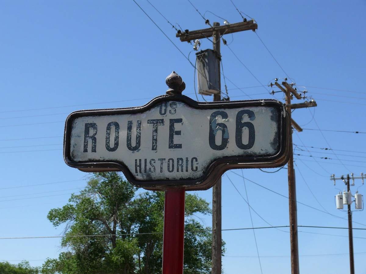 Panneau vintage Route 66 accroché à un poteau sous un ciel clair