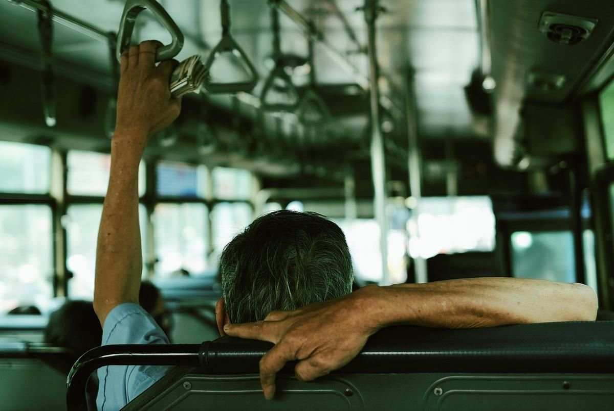 Intérieur d'un bus avec une personne debout, une main sur le palier et des fenêtres floues