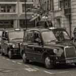 Des taxis noirs en rangée sur une rue de ville, piéton à droite