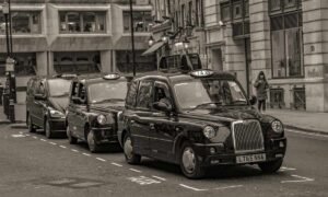 Des taxis noirs en rangée sur une rue de ville, piéton à droite