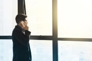 Homme en costume noir parlant au téléphone près d'une grande fenêtre