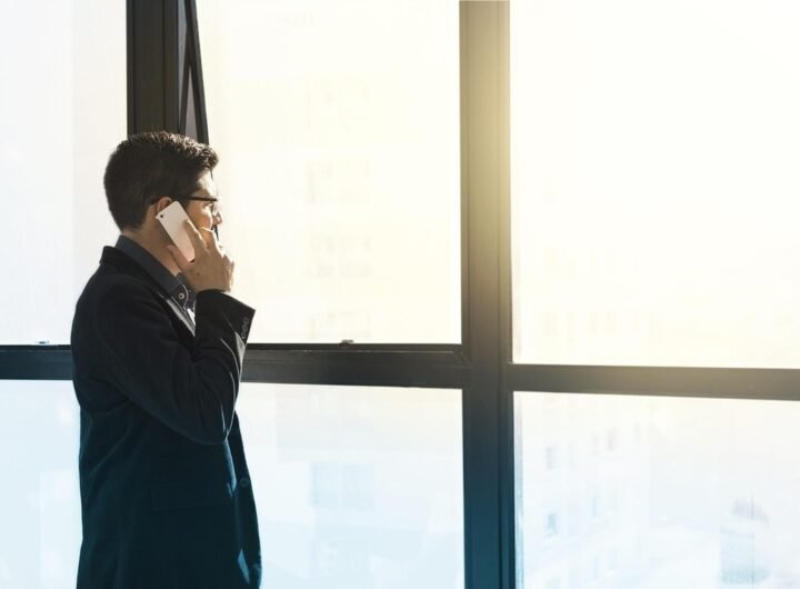 Homme en costume noir parlant au téléphone près d'une grande fenêtre