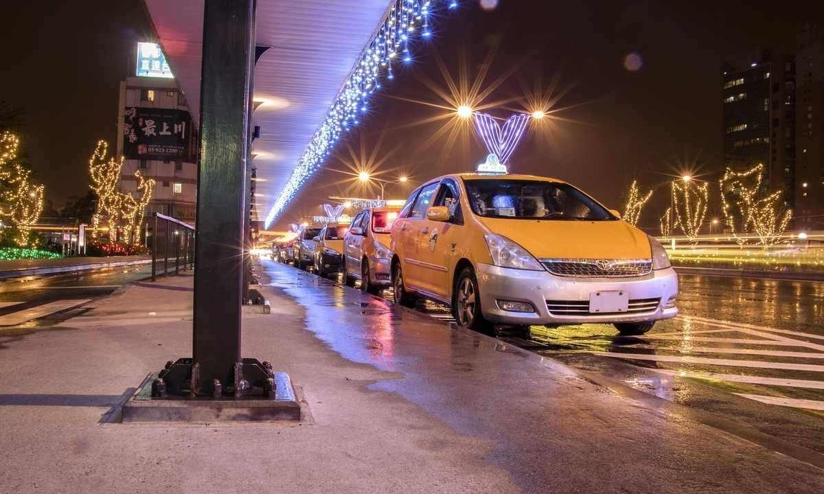 Des taxis jaunes attendent sous un pont décoré de lumières