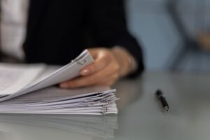 Main tenant classeur de documents sur table, stylo à côté