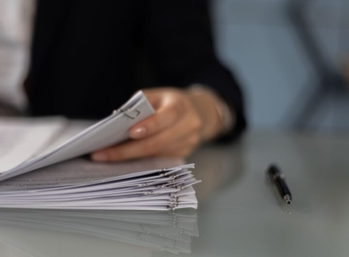 Main tenant classeur de documents sur table, stylo à côté