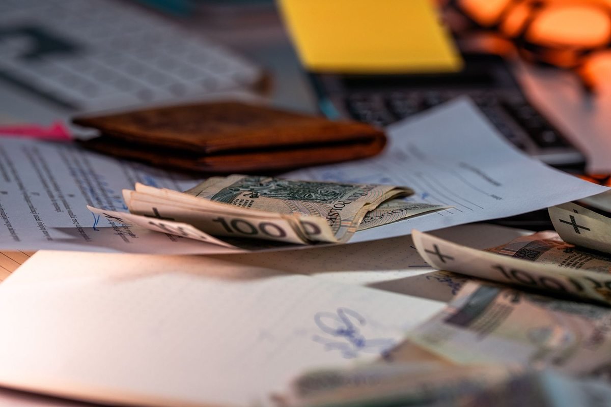Billets de 100 dollars éparpillés sur une table avec un portefeuille, des papiers et un clavier