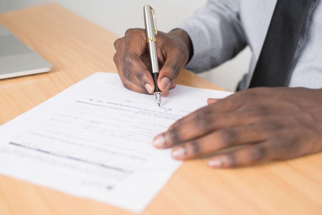 Main écrivant sur document avec stylo sur un bureau en bois