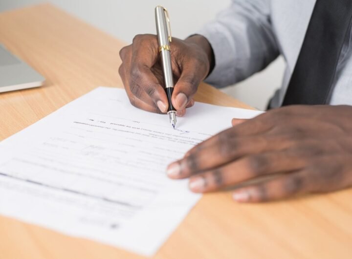Main écrivant sur document avec stylo sur un bureau en bois