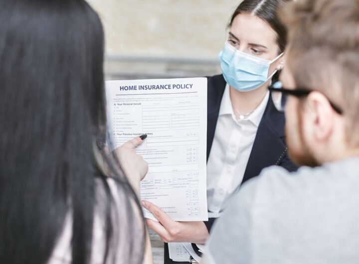 Une femme en masque montre un document d'assurance à deux clients