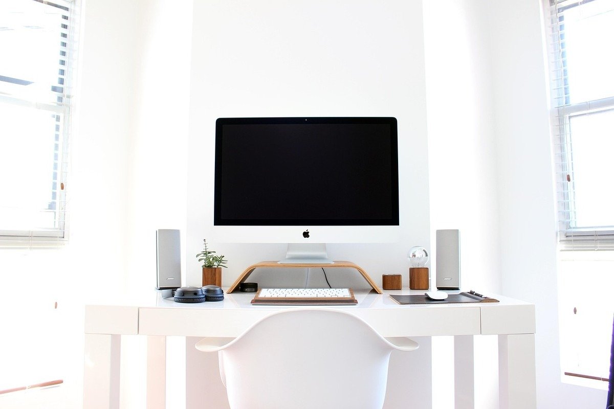 Bureau épuré blanc avec moniteur noir, chaise et objets de décoration, fenêtres latérales Bureau épuré blanc avec moniteur noir, chaise et objets de décoration, fenêtres latérales