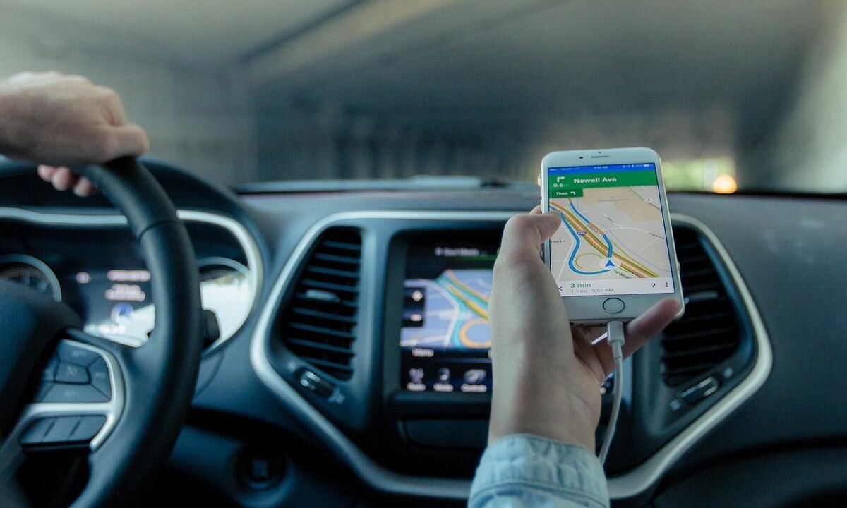 Une main tient un smartphone affichant une carte routière dans une voiture