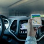 Une main tient un smartphone affichant une carte routière dans une voiture