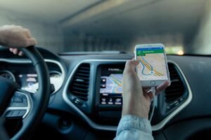 Une main tient un smartphone affichant une carte routière dans une voiture