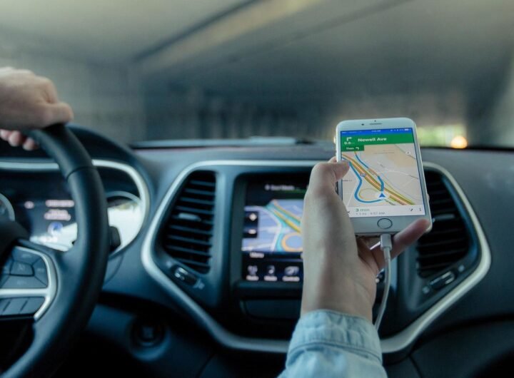 Une main tient un smartphone affichant une carte routière dans une voiture
